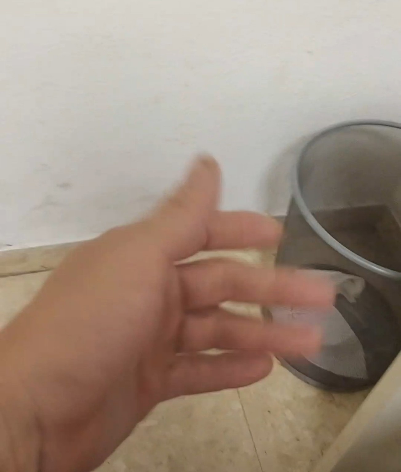 Una mano junto a una papelera